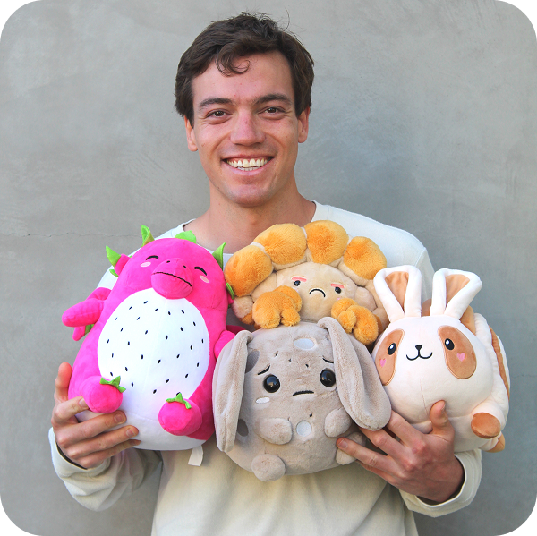 mikey holding four but cute plush characters: luna, dulce, claude, and peeko.